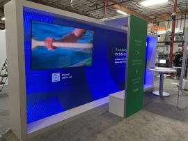 RENTAL: RE-2119 Inline Design with White Laminated Framed Single-Sided Lightbox, Arch Canopy Structure, Large Monitor Mount, RE-704 Charging Station Table, 75" Monitor, SEG Backlit Fabric Graphic, and Vinyl Applied Graphic